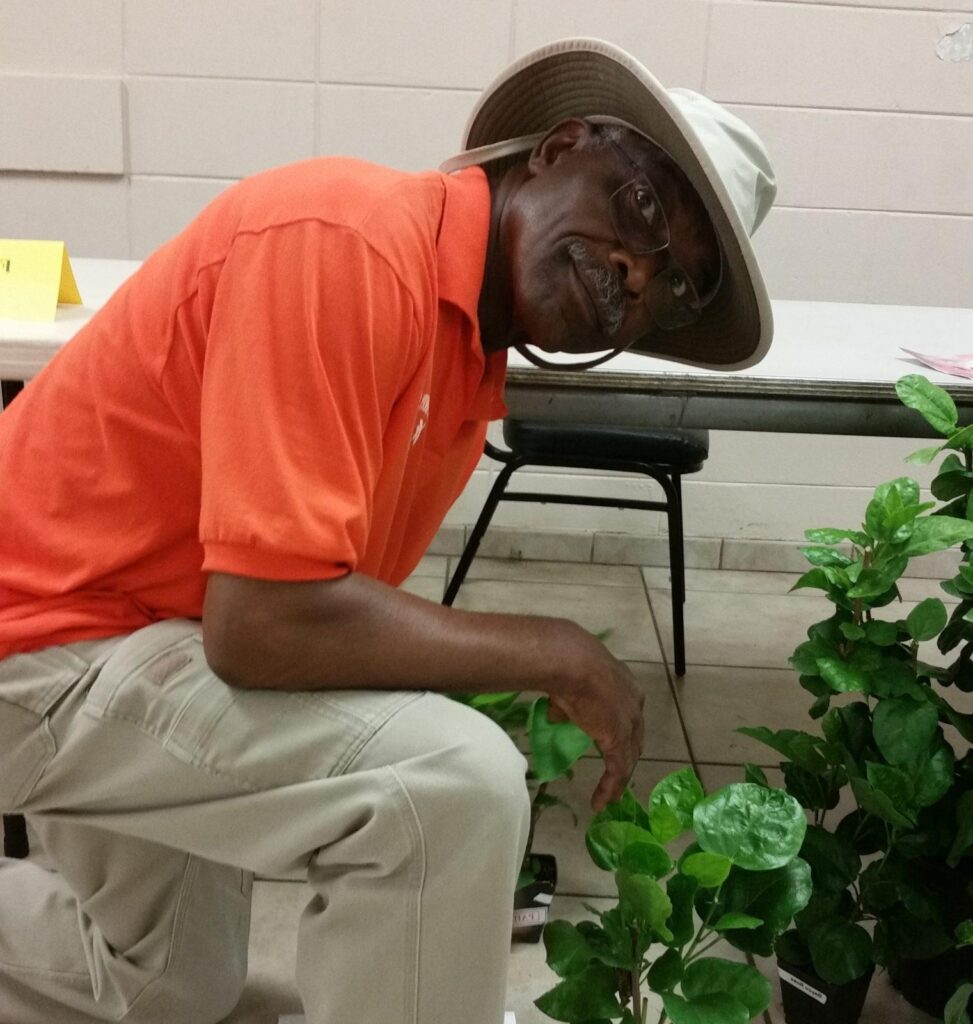 Man in orange shirt using a microscope outdoors.
