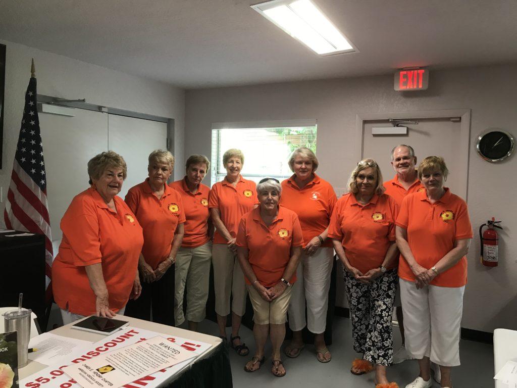 Group of people in orange shirts posing indoors.