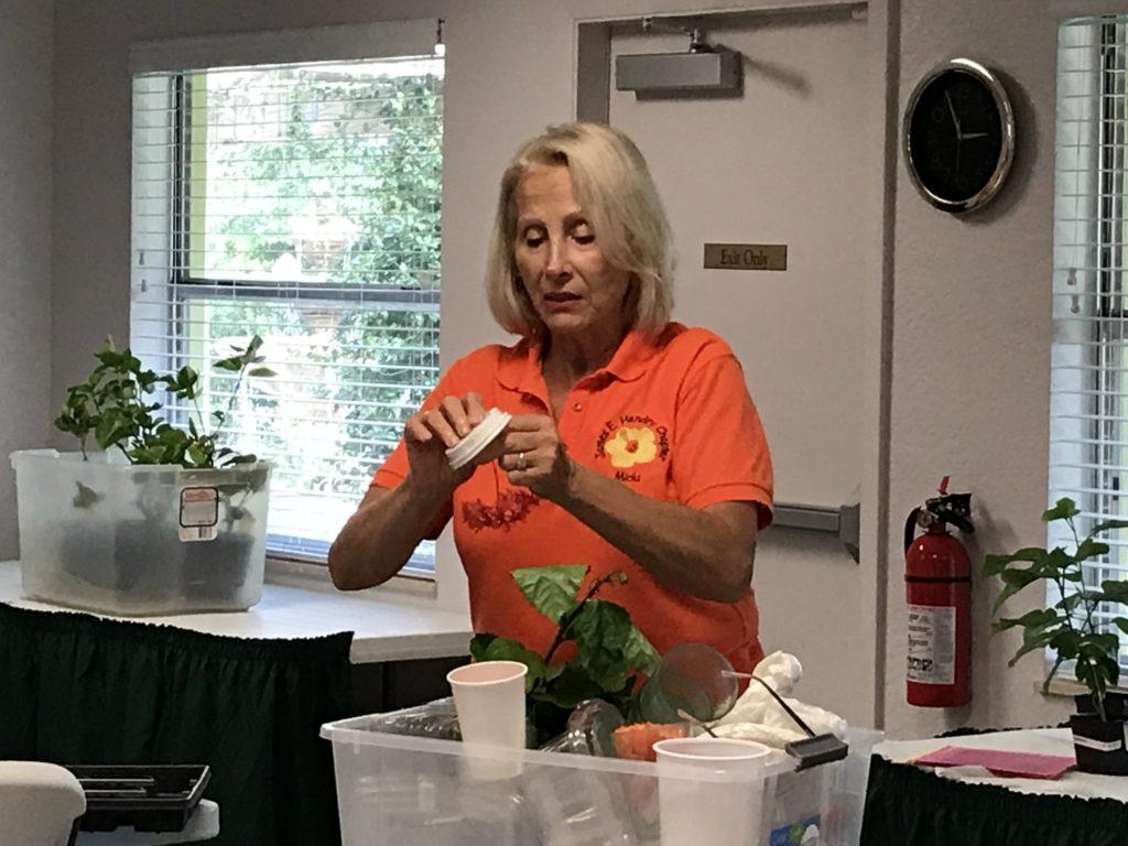 A woman preparing food in a kitchen wearing an orange shirt.