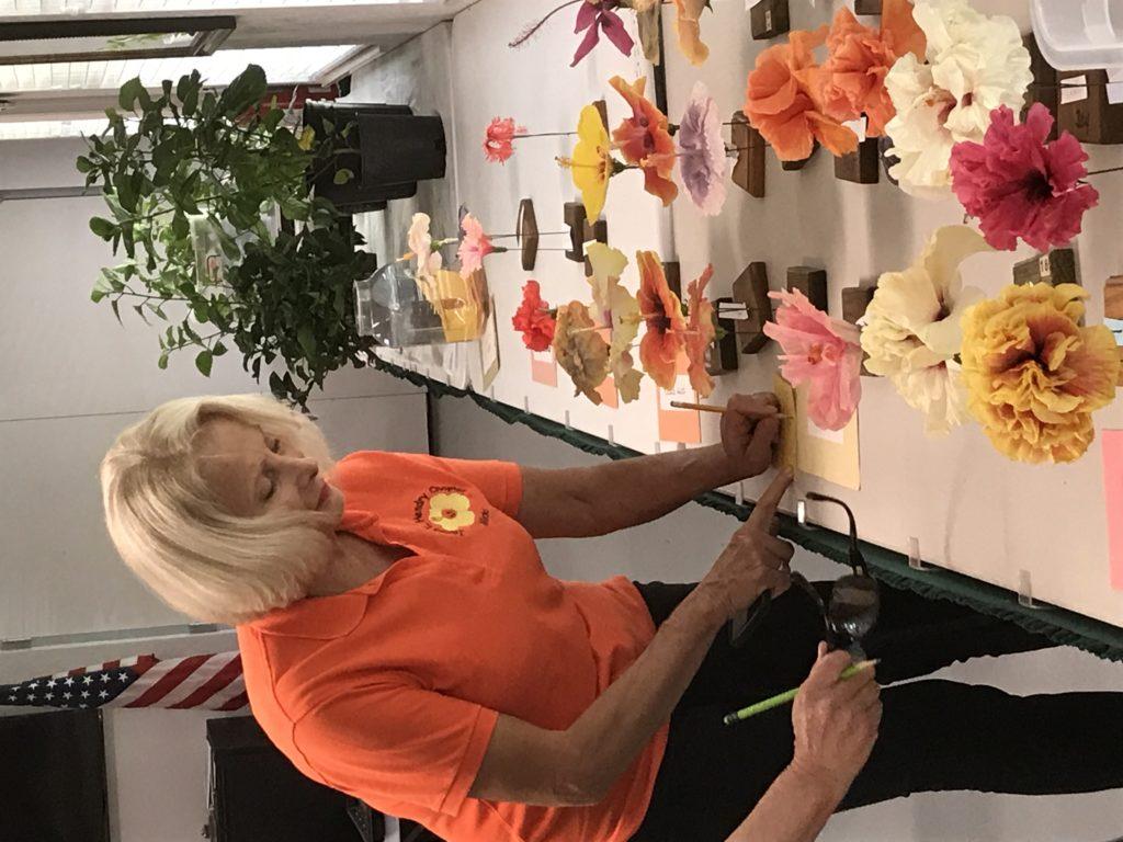 A woman arranging colorful flowers on a table outdoors.