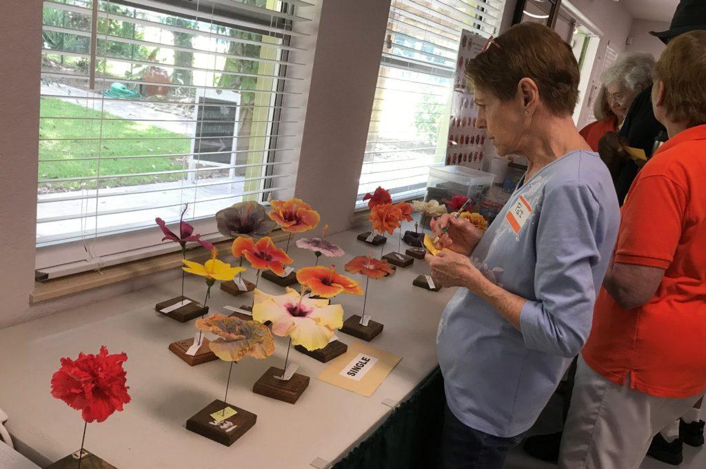 A person arranging colorful clay pieces on a table by a window.