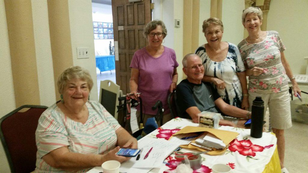 A group of four elderly women crafting together at a table.