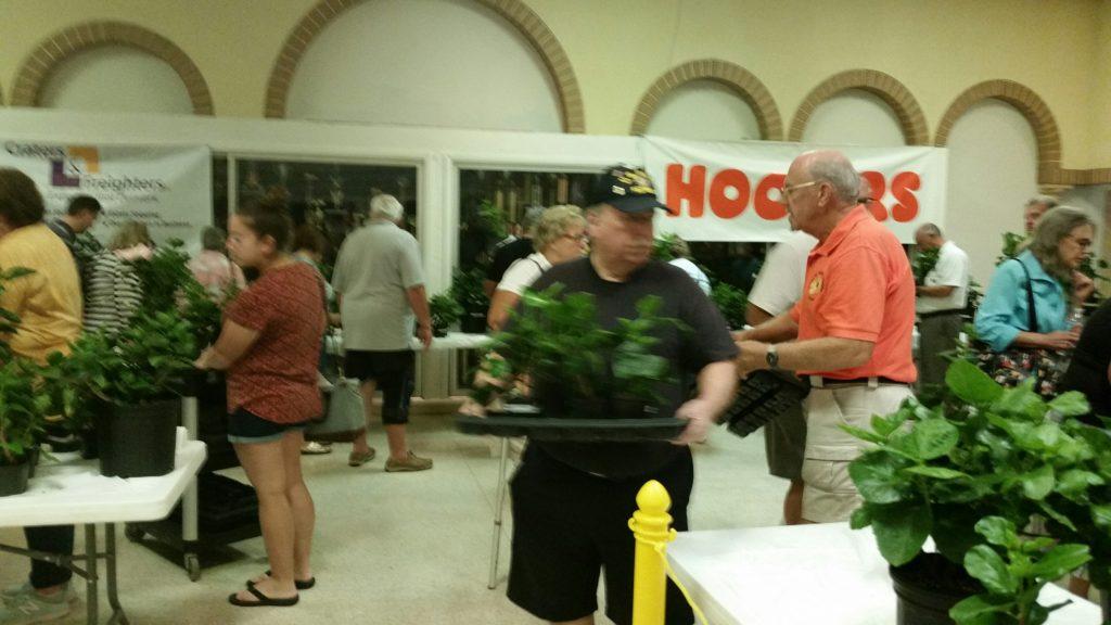 Three men standing and interacting near a table with food in an indoor setting.