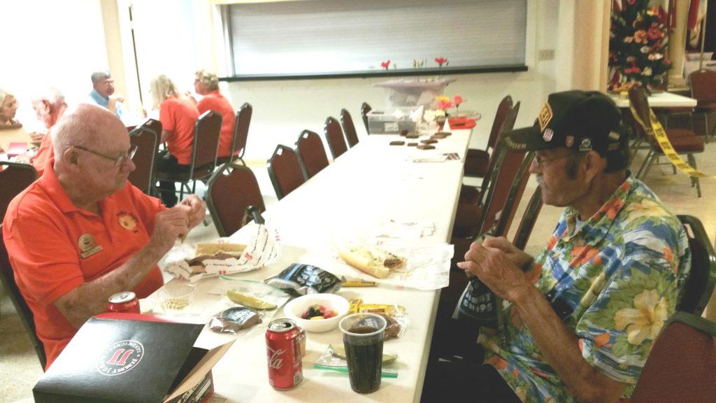 People gathered around a table with food and drinks in a casual setting.