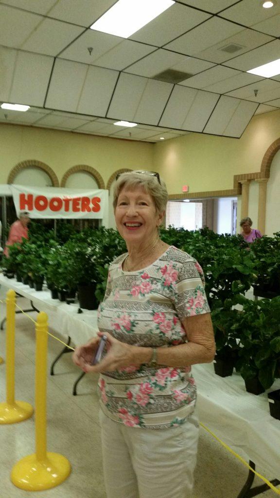 Smiling woman holding flowers in a greenhouse.