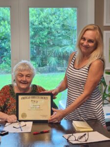 Two women smiling, one holding a framed certificate.